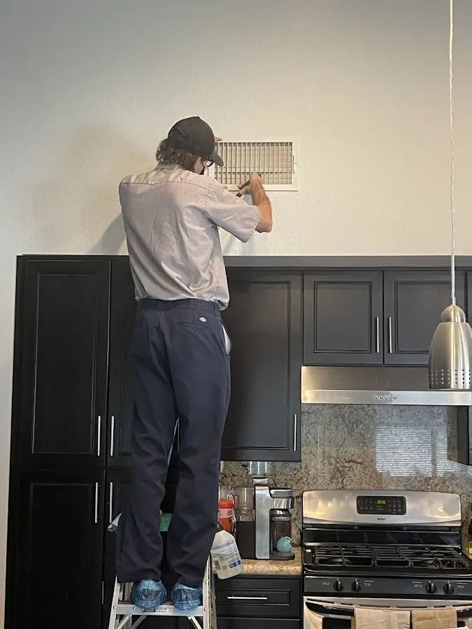 Technician inspecting an air vent during HVAC service in North Laurel
